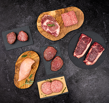 Assorted raw meats on wooden and black plates with a dark background